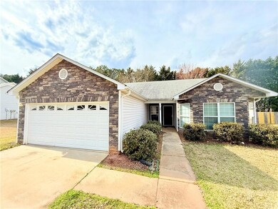 Single story home with concrete driveway, stone si