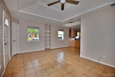 Unfurnished living room featuring a tray ceiling, visible vents, and baseboards