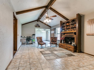 Living area featuring an office area, ceiling fan, a textured wall, a fireplace, and light tile patterned floors
