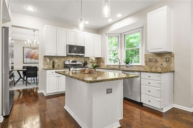 Kitchen with appliances with stainless steel finishes, a sink, dark stone counters, white cabinetry, and recessed lighting