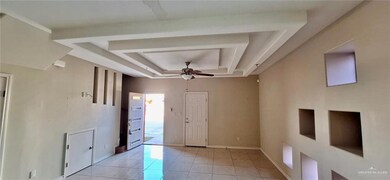Empty room with a tray ceiling, baseboards, light tile patterned flooring, and a ceiling fan