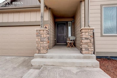 Property entrance featuring stone siding, an attached garage, and board and batten siding