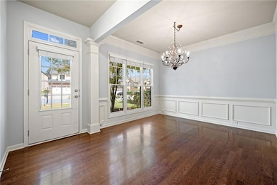 Entryway featuring dark wood finished floors, decorative columns, crown molding, a wainscoted wall, and a decorative wall
