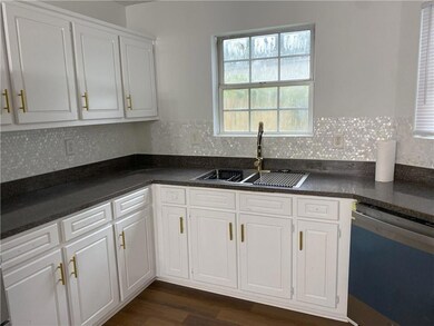 Kitchen with dishwasher, a sink, dark countertops,