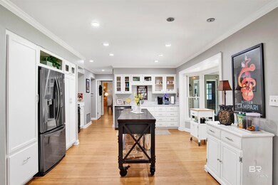 Kitchen featuring white cabinetry, glass insert cabinets, ornamental molding, appliances with stainless steel finishes, and light wood-style flooring