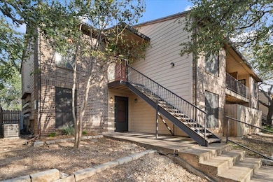 View of front of property featuring stairs, a balcony, and brick siding
