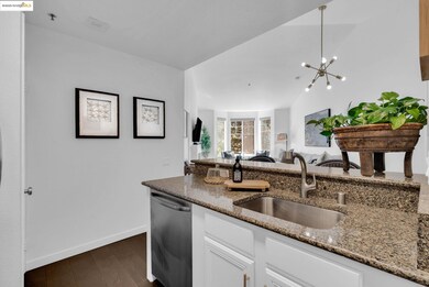 Kitchen with white cabinets, dark stone countertops, dark wood-style flooring, dishwasher, and open floor plan
