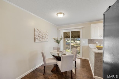 Dining area with ornamental molding, a textured ceiling, and dark wood-style floors