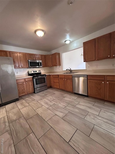 Kitchen featuring fridge, range, light countertops, dishwasher, and brown cabinets