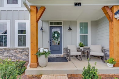 Property entrance featuring board and batten siding, covered porch, and stone siding