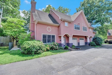 View of front facade featuring a garage, stucco siding, a chimney, and asphalt driveway