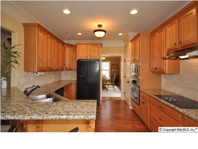 FABULOUS LIGHT FILLED KITCHEN BOASTS CUSTOM CABINTRY, GRANITE COUNTERS, TRAVERTINE BACKSPLASH AND STAINLESS APPLIANCES.