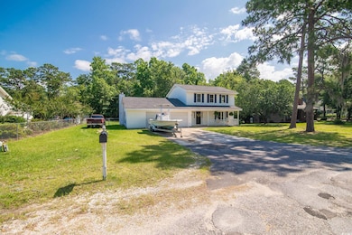 View of front of property with an attached garage, asphalt driveway, a chimney, and view of wooded area