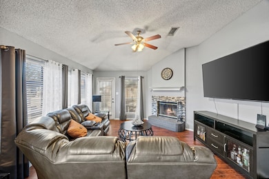 The living room features vaulted ceilings and a cozy glass covered  fireplace.