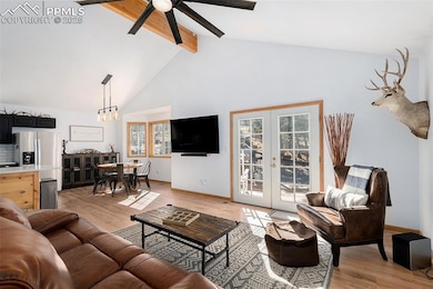 Living area with light wood-style flooring, high vaulted ceiling, beam ceiling, a ceiling fan, and french doors