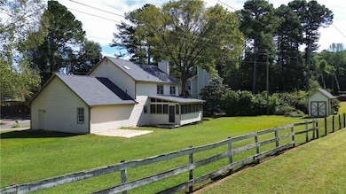 Rear view of house with a sunroom, a shingled roof, a shed, and a chimney