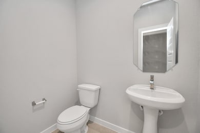 This half bathroom features a stylish pedestal sink, modern hardware, and bright recessed lighting, creating a sleek and inviting space. Sample photo of completed home with similar floor plan. Actual colors and selections may vary.
