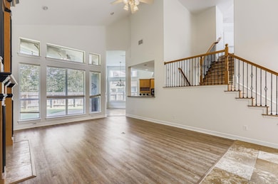 Unfurnished living room with high vaulted ceiling, light wood-style floors, and a ceiling fan