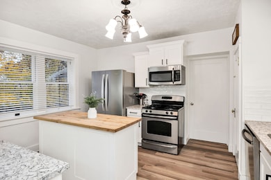 Kitchen featuring appliances with stainless steel finishes, tasteful backsplash, wood counters, white cabinetry, and a textured ceiling