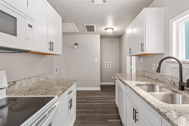 Kitchen featuring white cabinetry, light stone cou