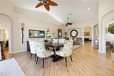 Dining space featuring a ceiling fan, arched walkways, lofted ceiling, and light wood-style floors