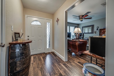 Foyer with a ceiling fan, dark wood-style flooring, and baseboards