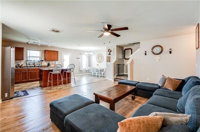 Living room featuring ceiling fan, light wood-type flooring, and a chandelier