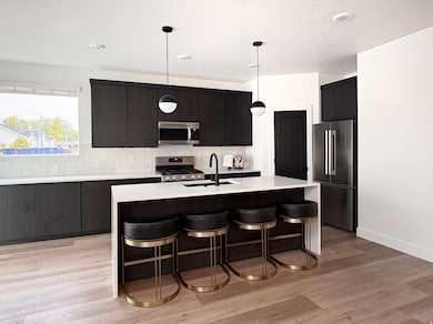 Kitchen featuring a kitchen breakfast bar, appliances with stainless steel finishes, hanging light fixtures, tasteful backsplash, and recessed lighting