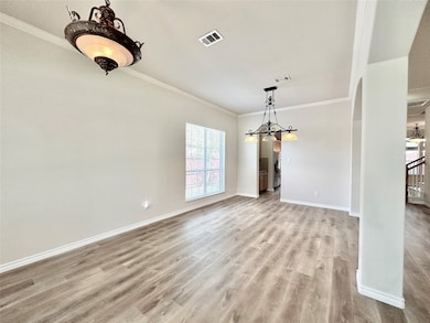 Unfurnished dining area featuring crown molding, arched walkways, and light wood finished floors