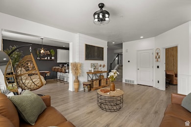 Living area with light wood-style flooring, stairway, and recessed lighting