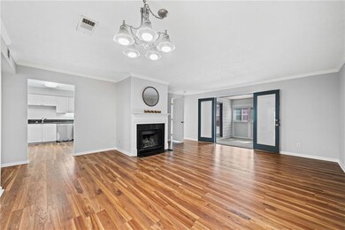 Unfurnished living room featuring baseboards, ornamental molding, wood finished floors, a chandelier, and a fireplace with flush hearth