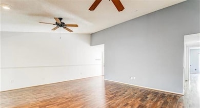 Unfurnished room featuring wood finished floors, ceiling fan, and high vaulted ceiling