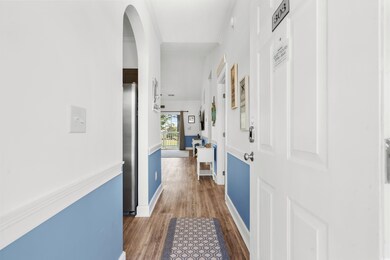 Hall with wood finished floors, arched walkways, and baseboards