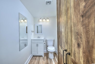 Bathroom featuring vanity, toilet, baseboards, woo