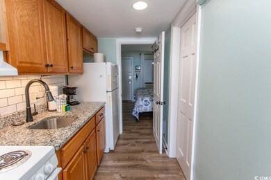 Kitchen with backsplash, light stone countertops, brown cabinetry, a sink, and wood finished floors