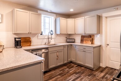 Kitchen with recessed lighting, dishwasher, a sink, gray cabinetry, and dark wood-style floors