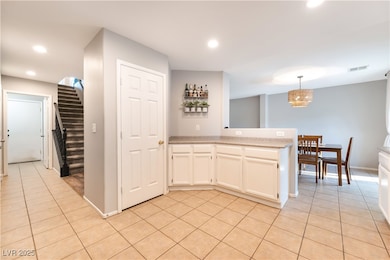 Kitchen with white cabinets, light tile patterned floors, pendant lighting, recessed lighting, and a peninsula