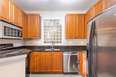 Kitchen with stainless steel appliances, a sink, and brown cabinetry