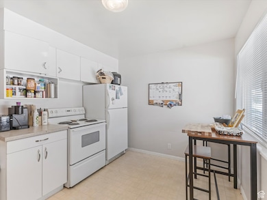 Kitchen with electric range, light countertops, white cabinetry, and light floors