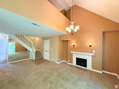 Unfurnished living room with carpet, stairs, a fireplace, a chandelier, and high vaulted ceiling