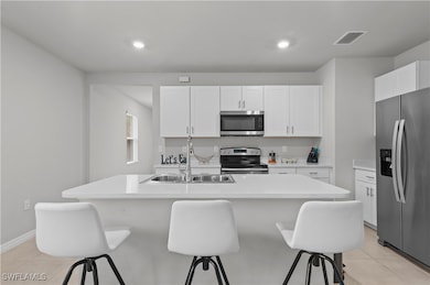 Kitchen with white cabinetry, appliances with stai