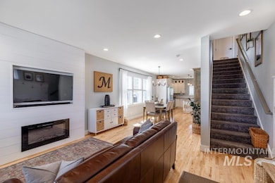 Living area featuring stairway, light wood-style flooring, a large fireplace, recessed lighting, and a chandelier
