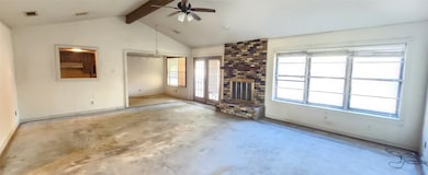 Unfurnished living room with beamed ceiling, unfinished concrete flooring, a ceiling fan, a brick fireplace, and high vaulted ceiling