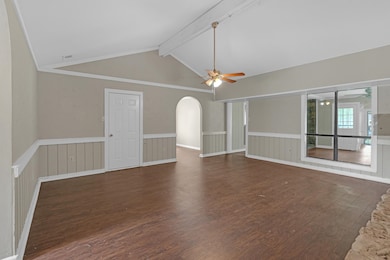 Unfurnished living room with dark wood-style floors, wainscoting, and ceiling fan