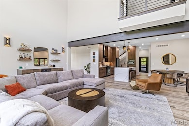 Living room featuring a high ceiling, bar, light wood-style flooring, and recessed lighting