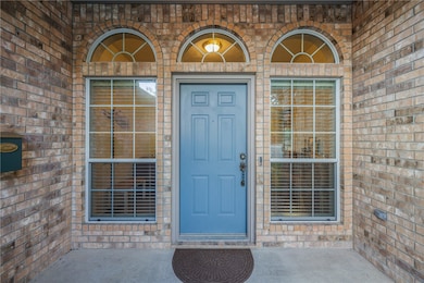 Doorway to property featuring brick siding and a patio