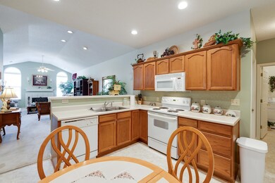 Kitchen featuring white appliances, a tile fireplace, a sink, a ceiling fan, and a peninsula
