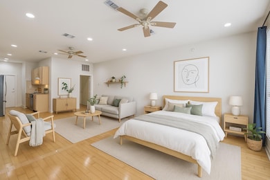 Bedroom with freestanding refrigerator, light woo