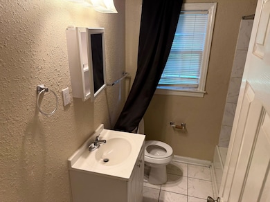 Bathroom with vanity, a textured wall, and marble look tile flooring