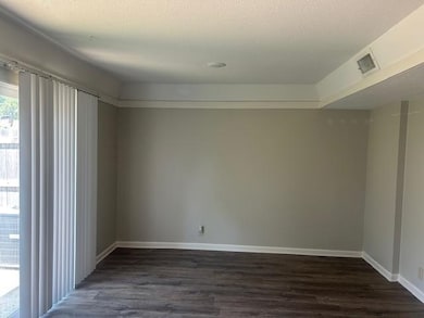 Spare room featuring dark wood-type flooring and baseboards